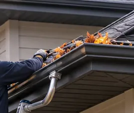 Autumn leaves being cleared from an eavestrough by hand